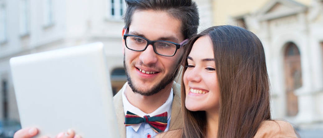 Man and woman looking happy while using tablet