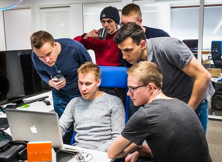 A team of Hibox developers working together around a laptop during a development day.